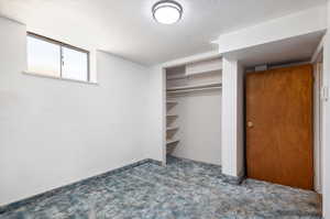 Unfurnished bedroom featuring a closet, a textured ceiling, and carpet flooring