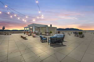 Patio terrace at dusk with a pergola, a mountain view, and an outdoor hangout area.