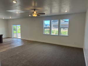 Carpeted empty room with a textured ceiling and ceiling fan