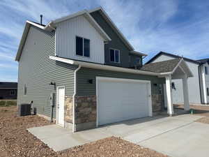 View of front of property with a garage and central AC unit