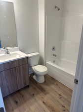 Full bathroom featuring wood-type flooring, bathtub / shower combination, toilet, and vanity