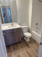 Full bathroom featuring vanity, shower / washtub combination, wood-type flooring, and toilet