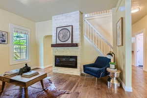 Living room with a fireplace, brick wall, and wood-type flooring