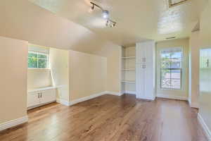 Additional living space with a textured ceiling and light hardwood / wood-style flooring