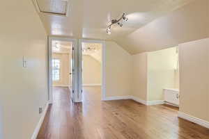 Additional living space featuring a textured ceiling, lofted ceiling, and hardwood / wood-style flooring