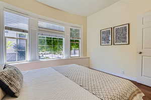 Bedroom with multiple windows and dark wood-type flooring