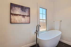 Bathroom with tile flooring and a bath to relax in