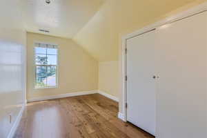 Additional living space with lofted ceiling, a textured ceiling, and hardwood / wood-style flooring