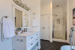 Bathroom with an enclosed shower, tile flooring, and vanity