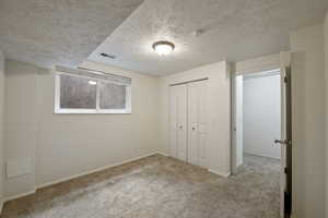 Unfurnished bedroom with a textured ceiling, a closet, and carpet floors