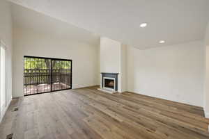 Unfurnished living room featuring light hardwood / wood-style floors and a towering ceiling