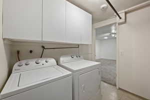 Laundry area with cabinets, a textured ceiling, washer hookup, independent washer and dryer, and light colored carpet