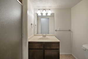 Bathroom featuring tile flooring, toilet, a textured ceiling, and large vanity