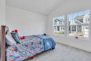 Carpeted bedroom featuring vaulted ceiling