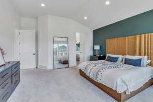 Carpeted bedroom featuring ensuite bathroom and vaulted ceiling