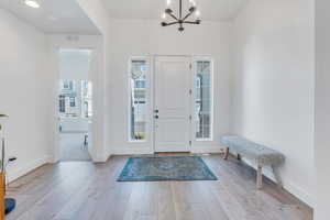 Foyer with light wood-type flooring and an inviting chandelier