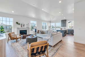 Living room featuring an inviting chandelier, light hardwood / wood-style flooring, and lofted ceiling