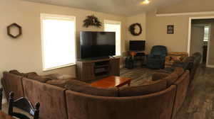 Living room with lofted ceiling, plenty of natural light, and dark hardwood / wood-style flooring