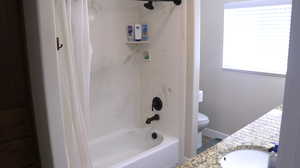 Full bathroom featuring shower / bathtub combination with curtain, vanity, and toilet