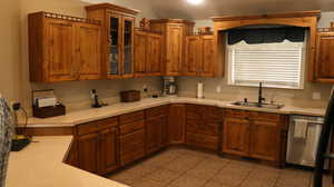 Kitchen featuring sink, dishwasher, and light tile floors