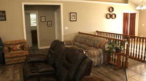 Living room featuring ornamental molding, dark wood-type flooring, lofted ceiling, and an inviting chandelier