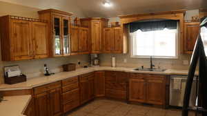 Kitchen featuring sink, dishwashing machine, and light tile flooring