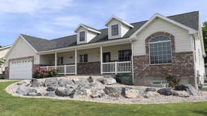 Cape cod house with a front yard, a porch, and a garage