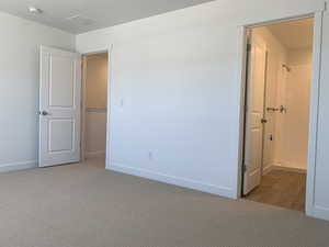 Unfurnished bedroom with ensuite bathroom and hardwood / wood-style floors