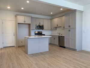 Kitchen with sink, light hardwood / wood-style floors, a kitchen island, and appliances with stainless steel finishes