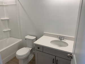 Full bathroom featuring hardwood / wood-style flooring, vanity, toilet, and shower / bathing tub combination