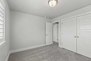 Unfurnished bedroom featuring light colored carpet and a closet