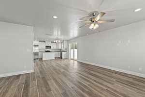 Unfurnished living room featuring a textured ceiling, sink, ceiling fan with notable chandelier, and wood-type flooring