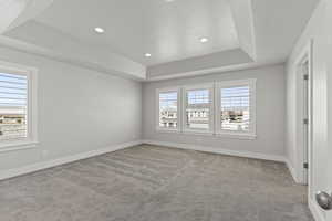 Carpeted spare room featuring a raised ceiling and a textured ceiling