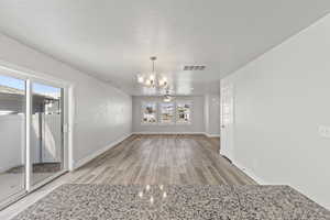 Unfurnished dining area with a textured ceiling, ceiling fan with notable chandelier, and hardwood / wood-style flooring