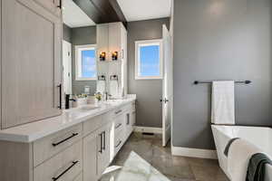 Bathroom featuring baseboards, double vanity, and a freestanding bath