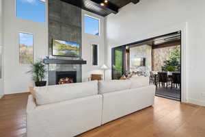 Living room featuring a towering ceiling, a fireplace, healthy amount of natural light, baseboards, and hardwood / wood-style floors