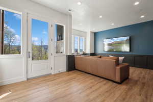 Living area featuring light wood finished floors, recessed lighting, and wainscoting