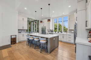 Kitchen featuring a center island, white cabinets, backsplash, and light wood-type flooring