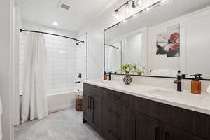 Full bathroom with double vanity and shower / bath combo with shower curtain
