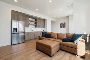 Living area with wet bar, light wood-style flooring, recessed lighting, and baseboards