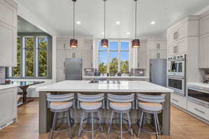 Kitchen featuring hanging light fixtures, stainless steel appliances, light hardwood / wood-style flooring, and tasteful backsplash