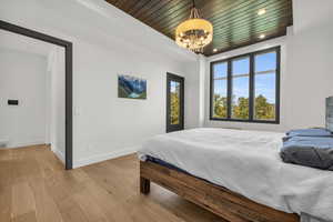 Bedroom featuring an inviting chandelier, hardwood / wood-style flooring, and wood ceiling