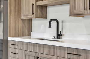 Interior space featuring sink, built in refrigerator, and light brown cabinetry