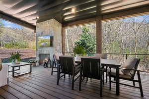 Wooden deck with an outdoor stone fireplace and outdoor dining area