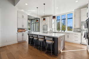 Kitchen with high quality fridge, backsplash, recessed lighting, a kitchen island with sink, and light countertops