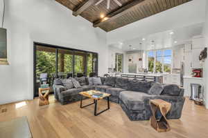 Living room with high vaulted ceiling, wooden ceiling, beamed ceiling, and light hardwood / wood-style flooring