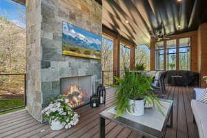 Wooden terrace with an outdoor stone fireplace and ceiling fan