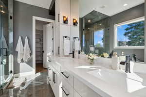 Full bath featuring a shower stall, recessed lighting, double vanity, and a walk in closet