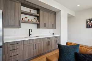 Kitchen featuring a sink, light wood-style flooring, light countertops, open shelves, and recessed lighting