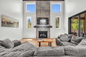 Living room featuring a high ceiling, a fireplace, and light wood-type flooring